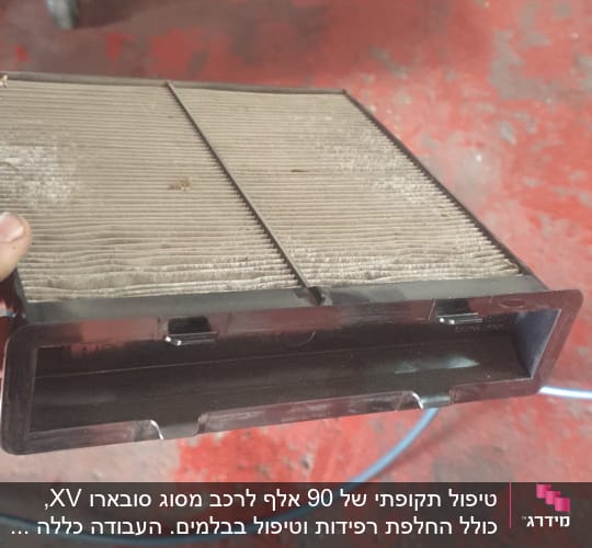 פילטר אוויר מלוכלך מוחזק ביד על רקע רצפה אדומה